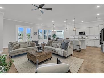 Open-concept living room with a ceiling fan, modern lighting, and access to the kitchen and dining areas at 663 Marsh Cove Cir, Summerville, SC 29486
