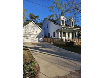 Charming two-story home with a white exterior, detached garage, a driveway and fenced front yard at 110 Cypress St, Summerville, SC 29483