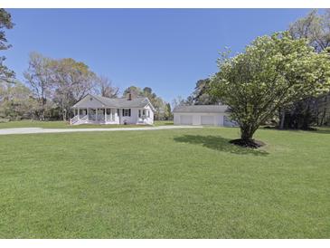 Charming home with large front yard, mature trees, and a detached three-car garage on a sunny day at 1298 French Santee Rd, Jamestown, SC 29453