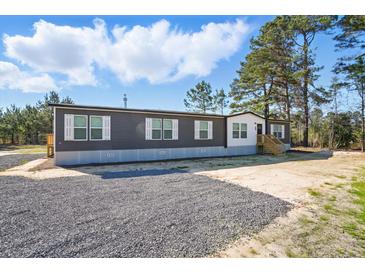 Exterior view of a modern home with gray siding, and a gravel area, showcasing its simple architecture at 1360 Burr Hill Rd, Cottageville, SC 29435