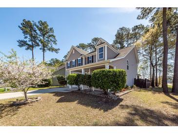 Charming two-story home with a well-manicured lawn, mature trees, and a welcoming front porch at 327 Freeland Way, Moncks Corner, SC 29461