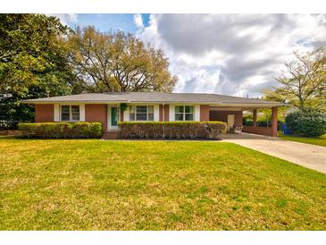 Charming red brick home with manicured lawn, carport, and lush trees offers classic curb appeal at 5040 Lancaster St, North Charleston, SC 29405