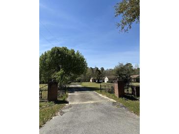Gated driveway with a long approach to the home and garage on a sunny day at 7819 Bells Hwy, Ruffin, SC 29475