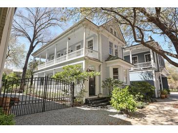 Charming two-story home features a spacious porch, black gate, and beautifully landscaped front yard at 99 Logan St, Charleston, SC 29401