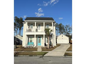 Charming two-story home boasts a covered porch, blue door and a well-manicured front yard, enhancing curb appeal at 149 Greenbelt Ct, Summerville, SC 29485