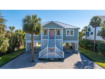 Charming coastal home with a brick driveway, staircase, and lush tropical landscaping at 3419 Myrtle St, Edisto Island, SC 29438