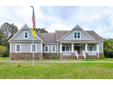 Charming two-story home with a stone facade, flag pole and a welcoming front porch at 4846 Causey Pond Rd, Awendaw, SC 29429