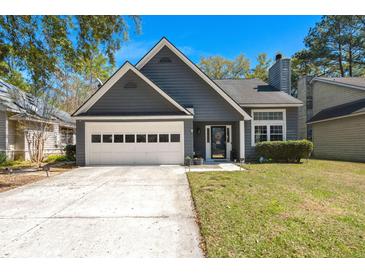 Charming home featuring a two-car garage, manicured lawn, and classic architectural details under a clear blue sky at 125 Mansfield Blvd, North Charleston, SC 29418