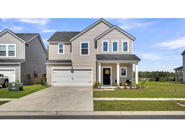 Charming two-story home featuring a spacious front lawn, attached garage, and welcoming entryway with decorative wreath at 157 Tuscan Sun St, Summerville, SC 29485