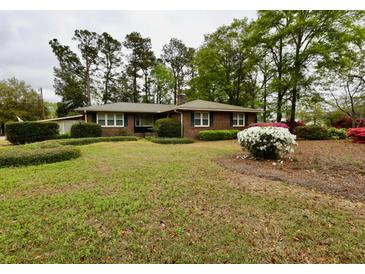 Charming brick home featuring a landscaped front yard with mature trees and colorful flowering bushes at 1636 Pinopolis Rd, Moncks Corner, SC 29461
