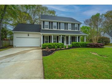 Charming two-story home featuring a spacious front porch, attached garage, and landscaped front yard with lush green lawn at 218 Candleberry Cir, Goose Creek, SC 29445