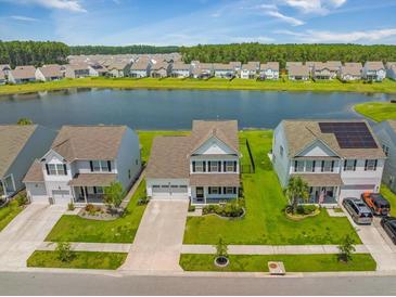 Stunning aerial view of homes lining a serene lake with lush green landscapes and community in the background at 260 Dunlin Dr, Summerville, SC 29486