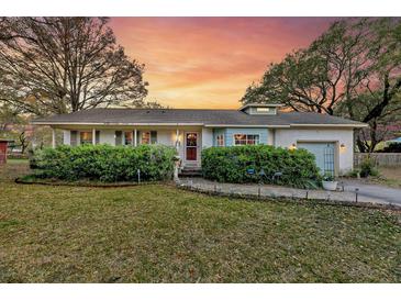 Charming one-story home with lush landscaping, brick walkway and inviting covered porch at sunset at 633 Schooner Rd, Charleston, SC 29412