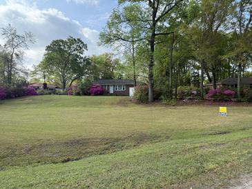 Charming one-story brick home with a spacious front yard and blooming azaleas at 1121 Inverness Ln, Hanahan, SC 29410