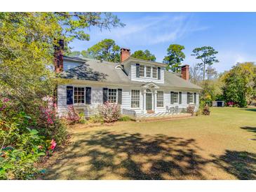Charming two-story home with white siding, black shutters, mature trees, and landscaped front yard at 1300 S Main St, Summerville, SC 29483