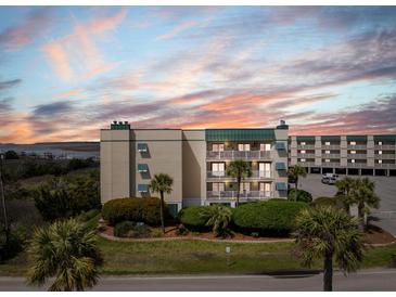 Stunning condo building with ocean views, balconies, and lush landscaping during a colorful sunset at 3701 Dock Site Rd # 302, Edisto Beach, SC 29438