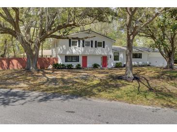 Charming two-story home featuring a white exterior, black shutters, and vibrant red doors at 703 Canary Dr, Charleston, SC 29414