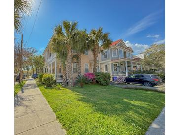 Charming two-story home with a front porch, palm trees, and a well-manicured lawn on a sunny day at 125 Ashley Ave, Charleston, SC 29401