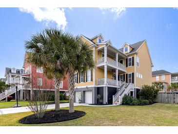 Stunning two-story yellow home with double balconies, landscaped yard, and a two-car garage at 138 Sandshell Dr, Charleston, SC 29492