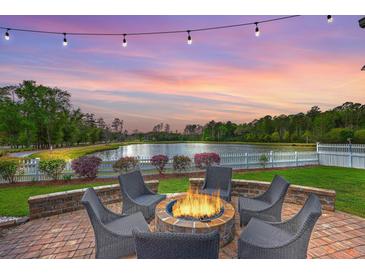 Outdoor fire pit with seating area, lake views, and string lights at dusk, perfect for relaxing and entertaining at 406 Summers Dr, Summerville, SC 29485