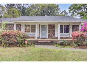 Charming brick home featuring a quaint front porch and colorful blooming shrubs enhancing its curb appeal at 407 Boone Hill Rd, Summerville, SC 29483