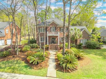 Charming two-story brick home featuring a balcony, manicured landscaping, and a welcoming entrance at 8795 E Fairway Woods Cir, North Charleston, SC 29420