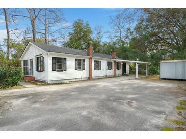 Charming exterior featuring white siding, black shutters, brick chimney, and ample parking space at 109 Gerideau St, Walterboro, SC 29488