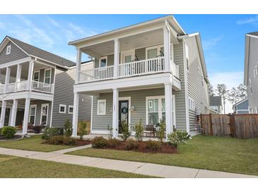 Inviting two-story home features a charming front porch and upper balcony, complemented by a well-maintained lawn at 183 Country Gate Lane Ln, Summerville, SC 29485