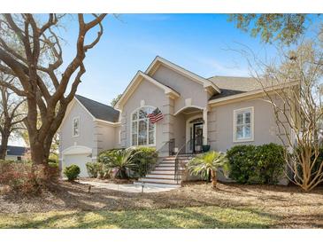 Charming home with a stucco facade, manicured landscaping, and an American flag at 3075 Maritime Forest Dr, Johns Island, SC 29455