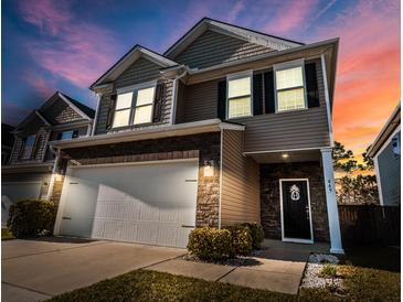 Charming two-story home with stone accents, a two-car garage, a manicured lawn, and inviting curb appeal at twilight at 449 Whispering Breeze Ln, Summerville, SC 29486