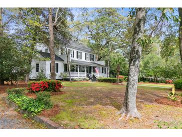 Charming two-story traditional home with a welcoming front porch, lush landscaping, and mature trees at 516 Central Ave, Summerville, SC 29483