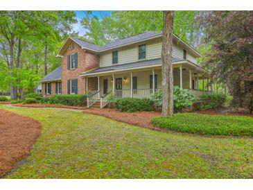Charming two-story home with brick accents, inviting porch, and mature landscaping in a wooded setting at 104 Huckleberry Ln, Summerville, SC 29485