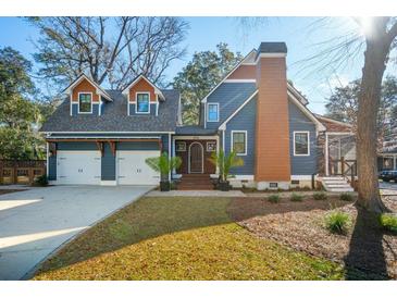 Charming blue home showcasing a two-car garage, front door, manicured lawn and blue skies at 1056 Wharf Indigo Pl, Mount Pleasant, SC 29464