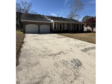 Charming single story brick home featuring an attached two car garage and large concrete driveway at 1561 Montclair St, Charleston, SC 29407
