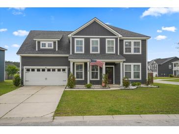 Charming two-story home boasts a well-manicured lawn, attached garage, and welcoming front porch with an American flag at 180 Basket Grass Ln, Summerville, SC 29486