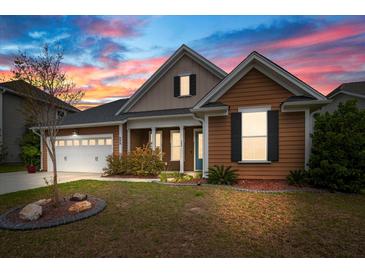 Charming home featuring colorful sky, well-manicured lawn, landscaping, covered porch, and two car garage at 404 Ambergate Ln, Moncks Corner, SC 29461
