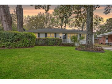 Charming single-story home featuring a lush green lawn, mature trees, and manicured landscaping at 5337 Hartford Cir, North Charleston, SC 29405