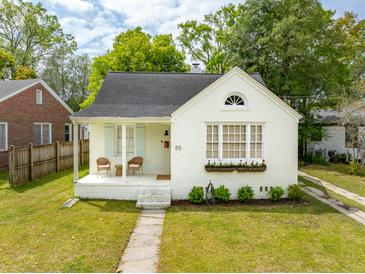 Charming white brick home featuring a covered porch with seating and a well-manicured front yard at 85 Colleton Dr, Charleston, SC 29407