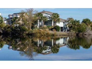 Stunning waterfront home reflecting on the lake, surrounded by lush greenery and palm trees at 1 Battery Park Rd, Edisto Island, SC 29438