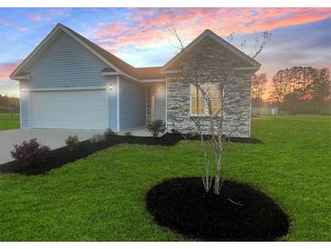 Charming single-story home with light blue siding, stone accent wall, manicured lawn, and two-car garage at 3292 N Highway 52, Saint Stephen, SC 29479