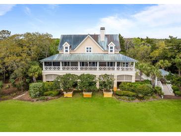 Beautiful exterior view of home with a metal roof, spacious porch, lush landscaping and mature trees at 377 Lofton Ct, McClellanville, SC 29458