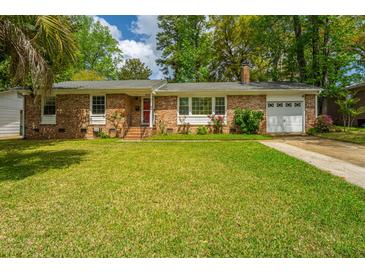 Charming brick home featuring lush landscaping, a well-manicured lawn, and an attached garage with driveway at 6018 Ridgecrest Ave, Hanahan, SC 29410