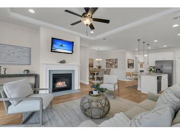 Inviting living room featuring a cozy fireplace, ceiling fan, and seamless flow to the dining area and kitchen at 614 Beach Way, Summerville, SC 29486