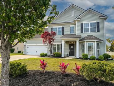 Charming two-story home featuring a well-maintained lawn, landscaping and attached two car garage at 7483 Hawks Cir, Hanahan, SC 29410