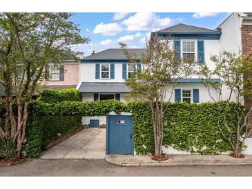 Charming two-story white home with blue shutters and a vine-covered wall for added privacy at 8 Poulnot Ln, Charleston, SC 29401