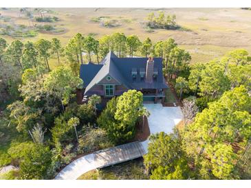 Aerial view of a wooded estate featuring a charming home and a marsh in the background at 83 Blue Heron Pond Rd, Kiawah Island, SC 29455