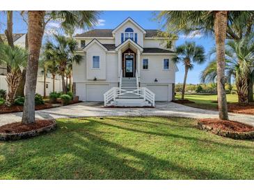 Charming two-story home with a well-manicured lawn, palm trees, and an inviting entrance at 9 Intracoastal Ct, Isle of Palms, SC 29451