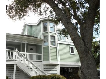 Charming coastal home with a light green exterior, white trim and a unique bay window feature at 2 Pelican Reach # Share 11, Isle of Palms, SC 29451