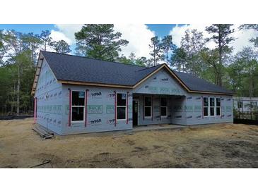 New construction shows classic home with dark roof and covered entry, surrounded by natural landscape at 277 W Smith St, Lincolnville, SC 29485