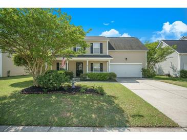 Charming two-story home featuring a well-manicured lawn, lush landscaping, and inviting front porch at 529 Beverly Dr, Summerville, SC 29485